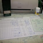 Dispatcher's tools of the trade: trainsheet, radio, clearance forms, aspirin. Not shown is a schematic reference of the dispatcher's territory mounted on cork board above the desk.